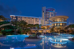 Un hotel con una piscina grande, palmeras y un tobogán de agua.