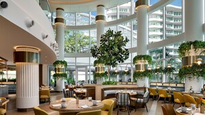 A spacious hotel lobby with multiple seating areas, large windows, and indoor plants. - Pier Sixty-Six (Pier 66) (Fort Lauderdale)