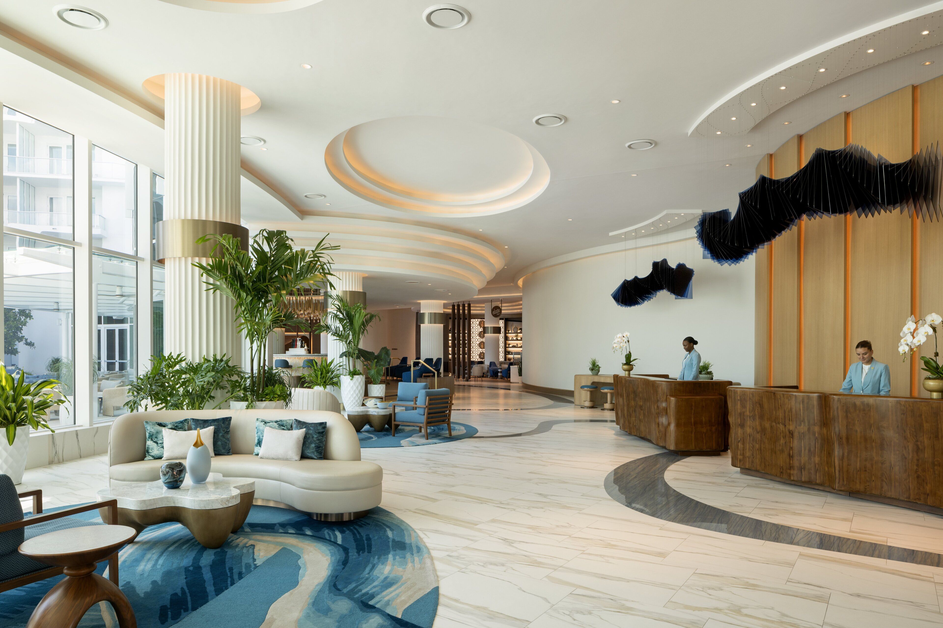 A spacious lobby with a reception desk, seating area, and large windows.