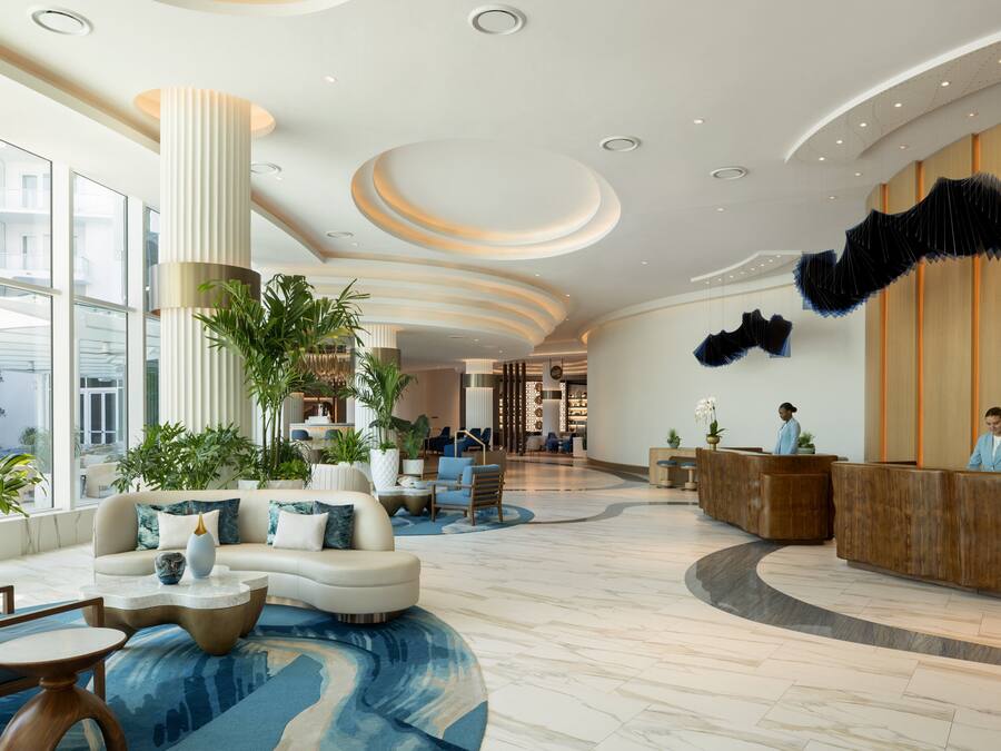 A spacious lobby with a reception desk, seating area, and large windows.