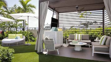 Un patio exterior con asientos, un televisor y vistas de la ciudad.