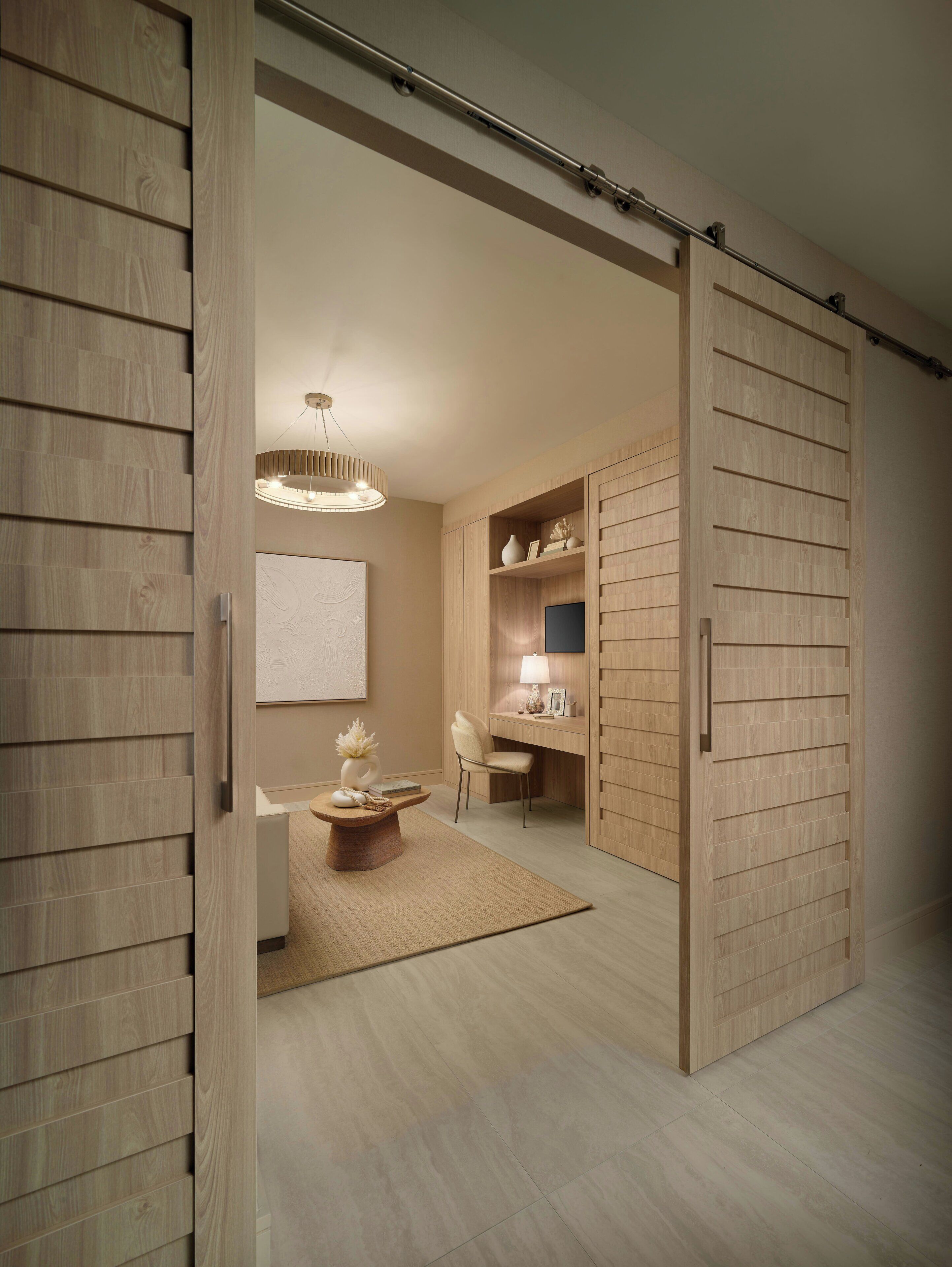 A modern interior with a sliding door closet, a desk with a chair, a hanging light fixture, and a small table with decorative items.