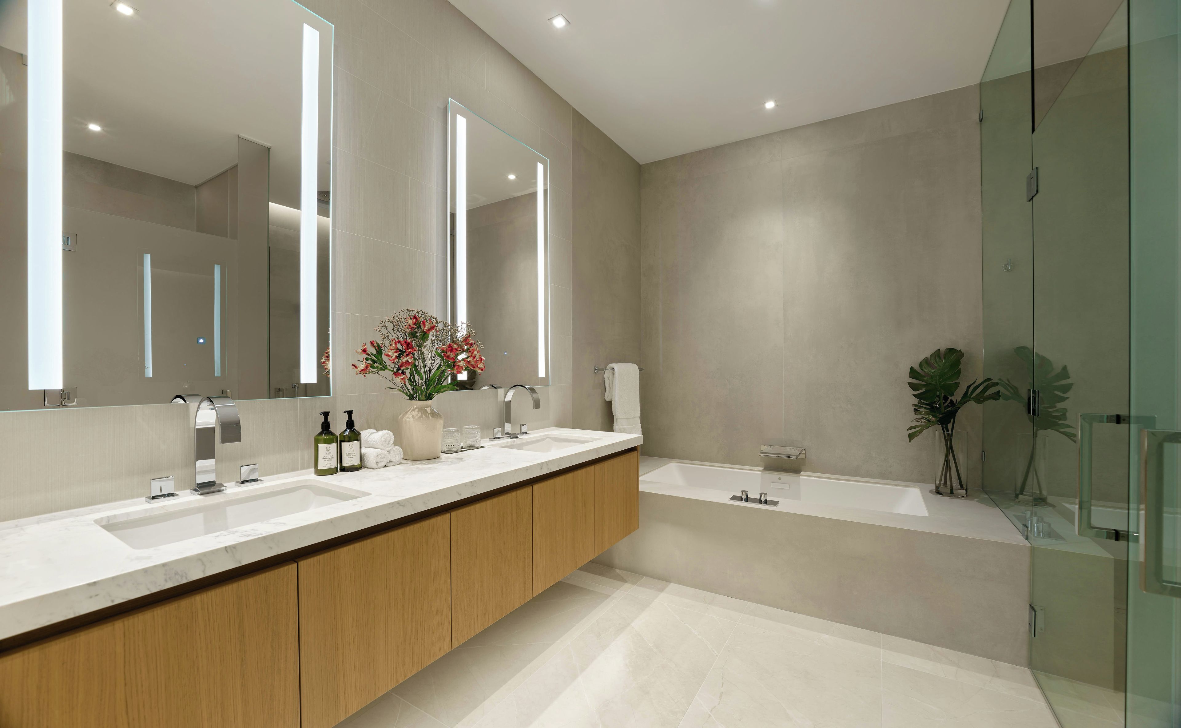 A modern bathroom with two sinks, a large mirror, a glass shower enclosure, and a potted plant.