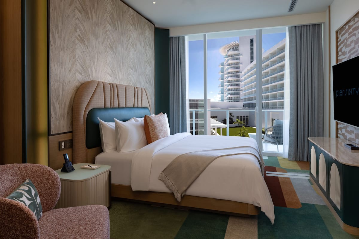 Habitación de hotel moderna con una cama grande, un escritorio y vistas a un edificio alto.