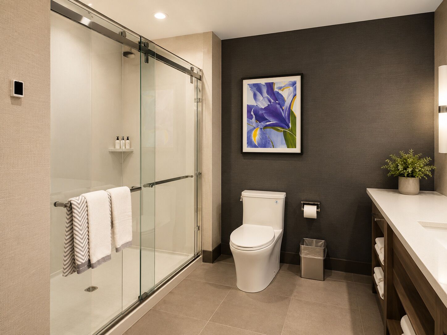 Un bagno moderno con box doccia in vetro, un water, un lavandino con specchio e una pianta in vaso.