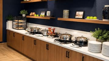 A kitchen with wooden cabinets, a countertop with various appliances, and decorative items on shelves.