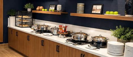 A kitchen with wooden cabinets, a countertop with various appliances, and decorative items on shelves.