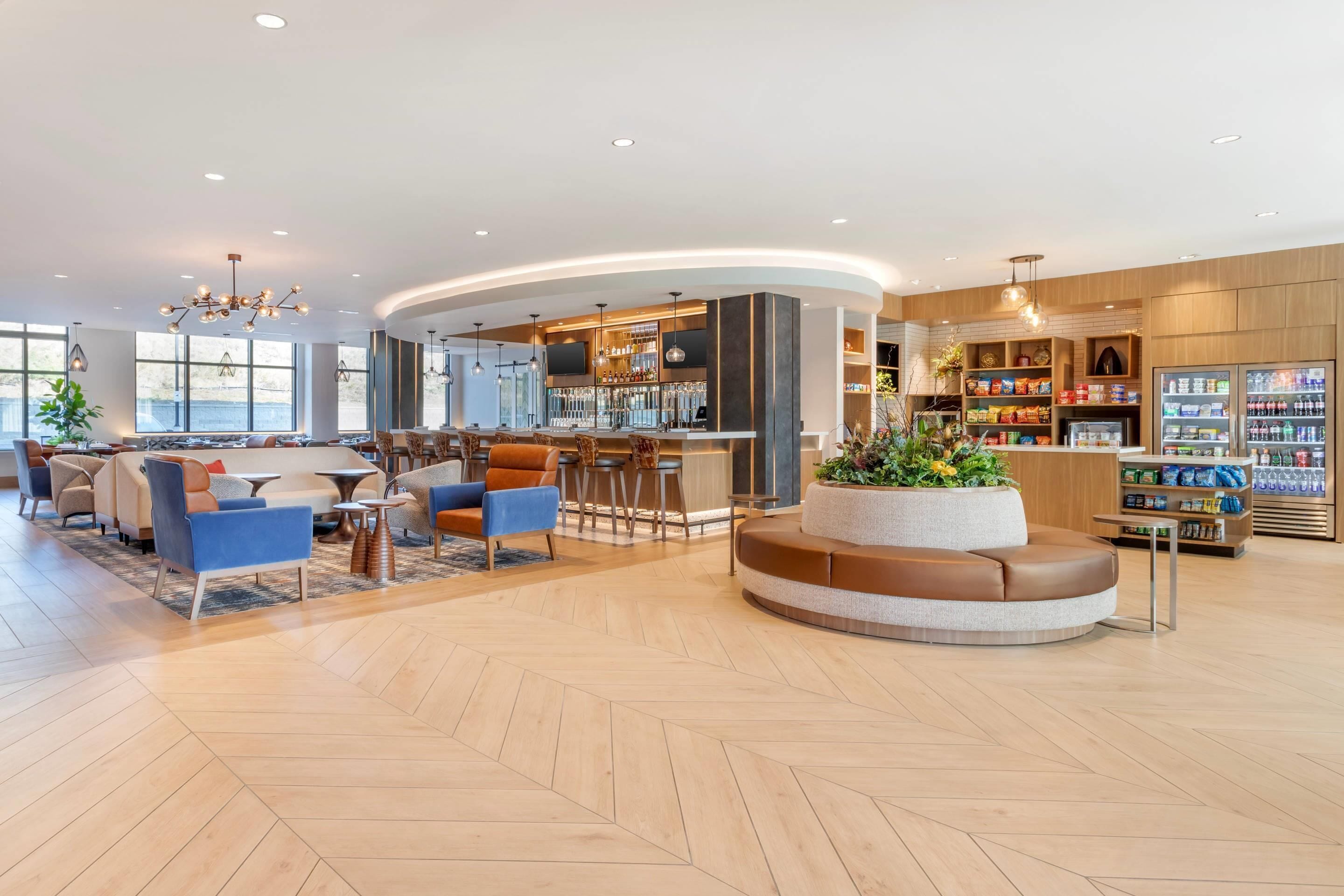 A modern hotel lobby with a bar area, seating arrangements, and a reception desk.
