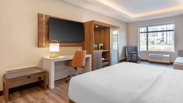 A hotel room with a bed, desk, chair, TV, and a window with a view.