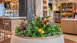 Un interior moderno con una mesa redonda central rodeada de diversas plantas y flores.