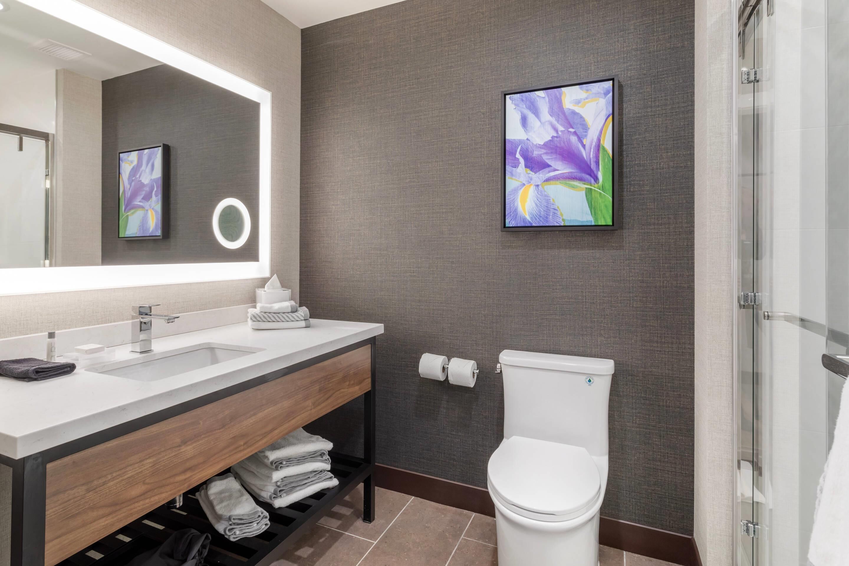 Un baño moderno con un espejo grande, dos lavamanos, un inodoro y una ducha.