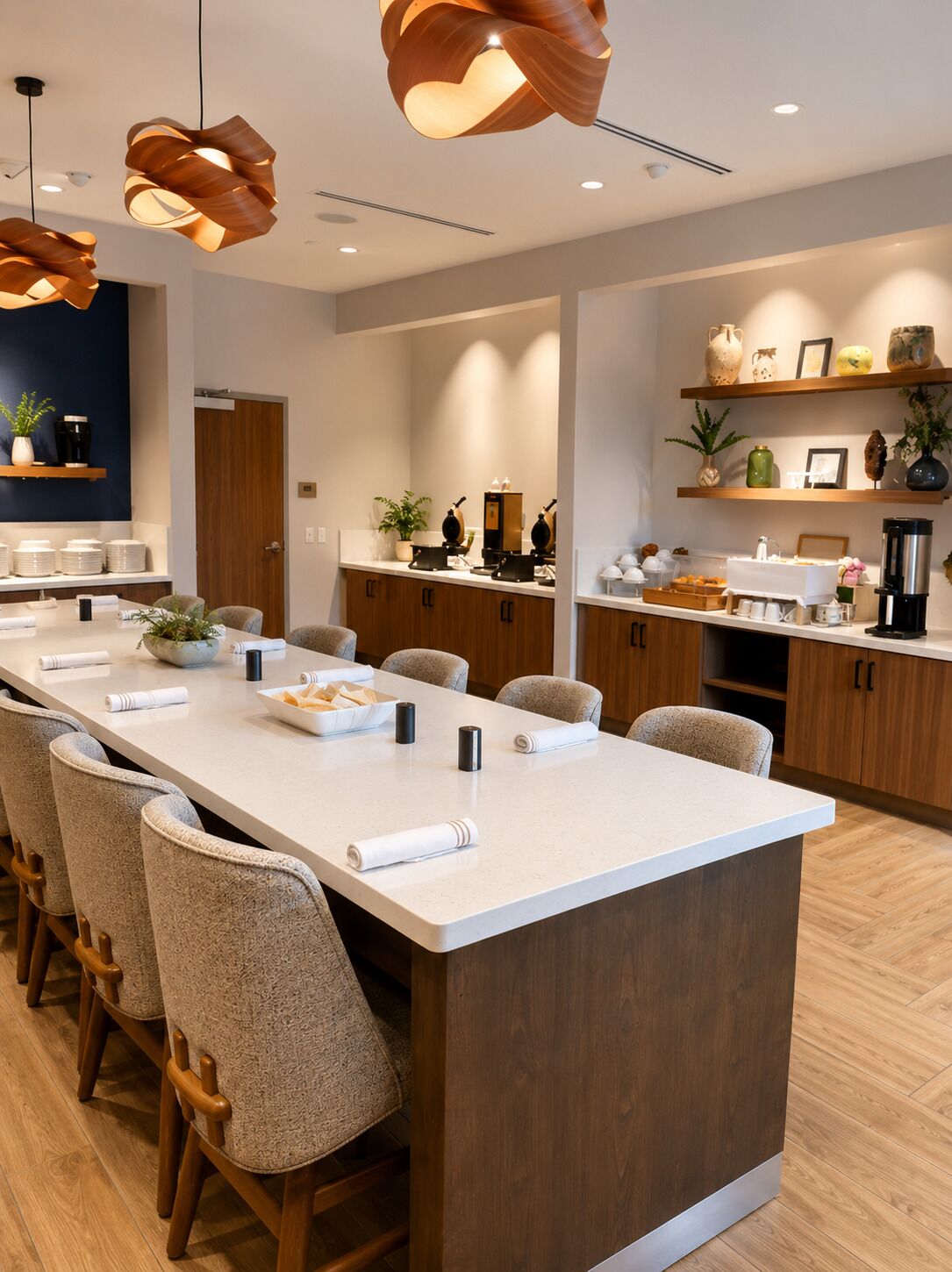 Una cocina moderna con una isla central, taburetes de bar, iluminación colgante y armarios de madera.