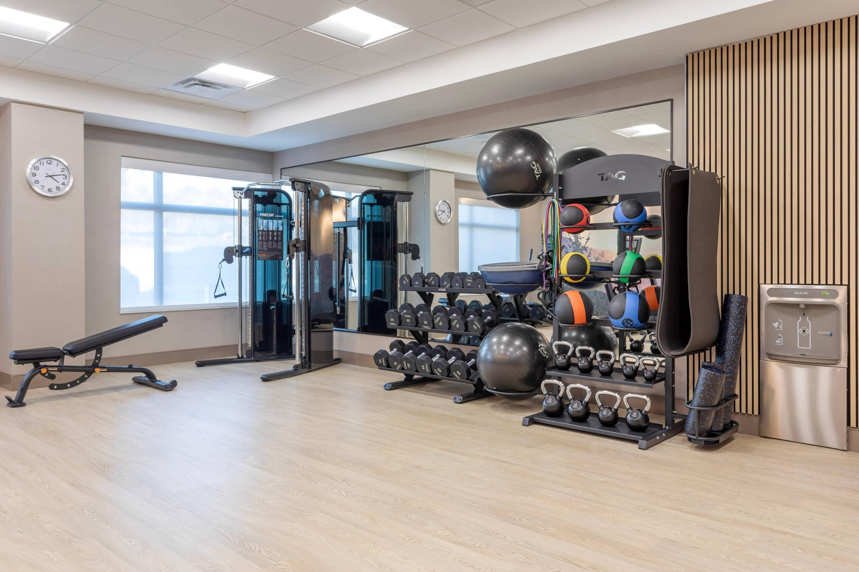 A gym with various exercise equipment, including dumbbells, kettlebells, and a bench.