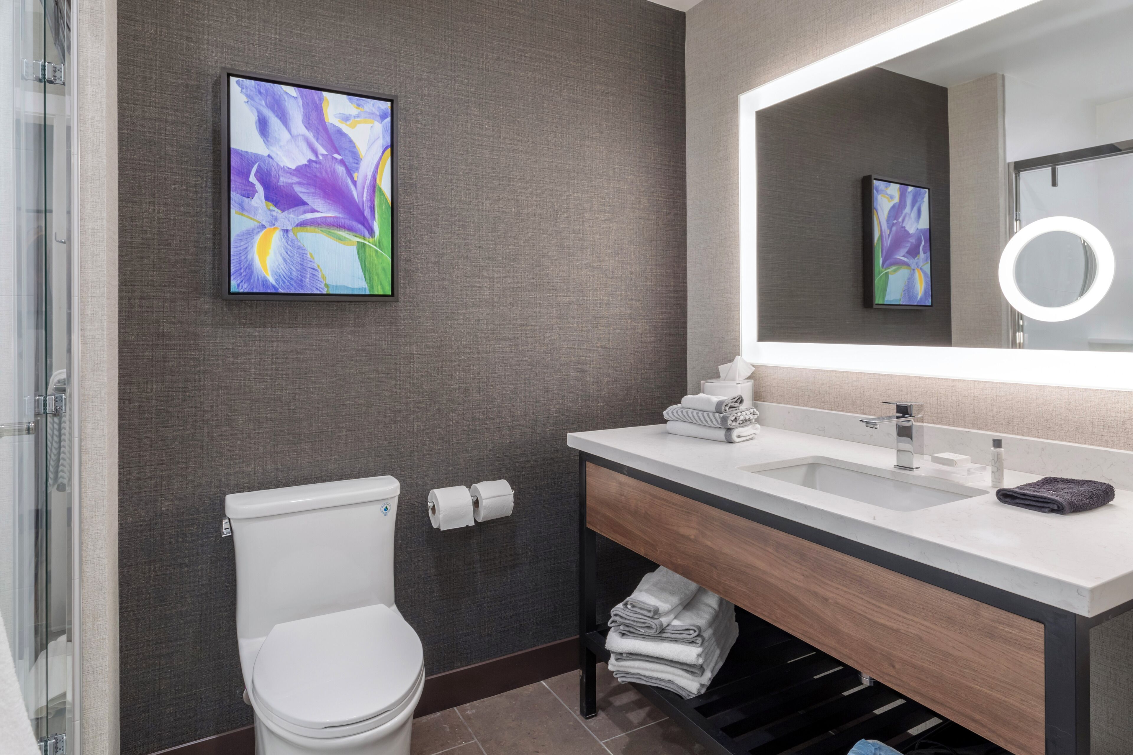 Een moderne badkamer met een wit toilet, een wastafel met spiegel en een douche.