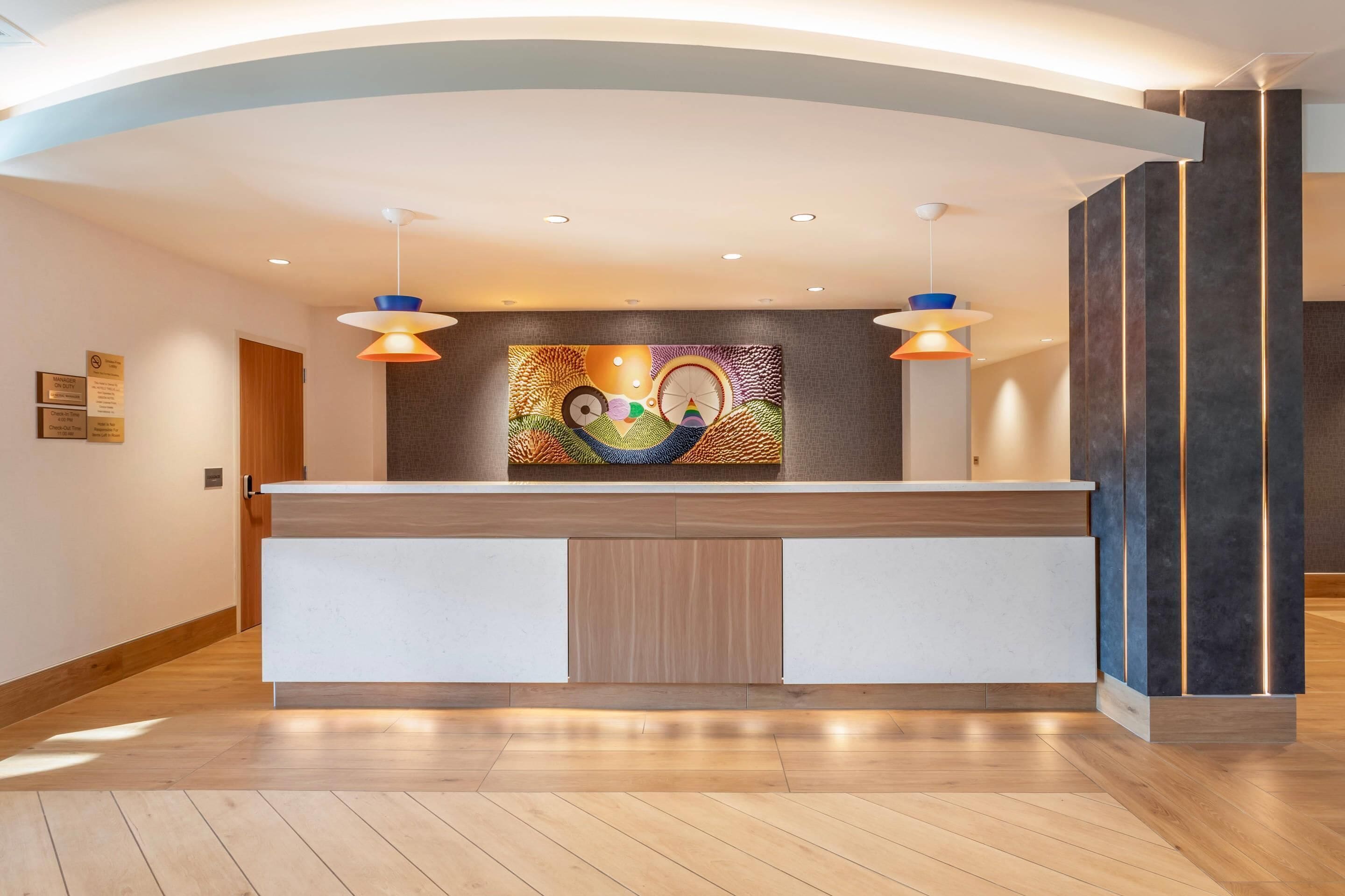 Un mostrador de recepción de diseño moderno, un mural en la pared y un suelo de madera.