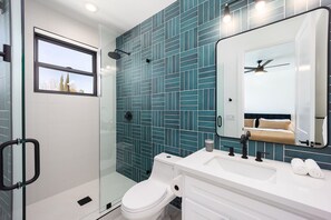 Une salle de bain moderne avec une douche à parois de verre, des toilettes blanches et un meuble-lavabo avec un miroir.