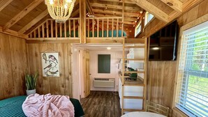 Interior acogedor de una cabaña con habitación en altillo, comedor y cocina.