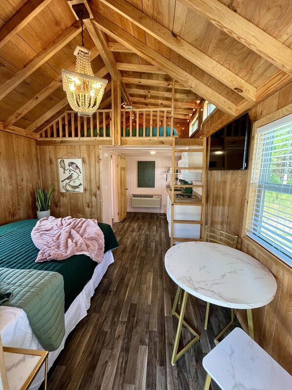 A cozy cabin interior with a loft bedroom, a dining area, and a kitchen. - Deluxe Loft Cabin - Upscale Cozy Loft Cabin (Bolivia)