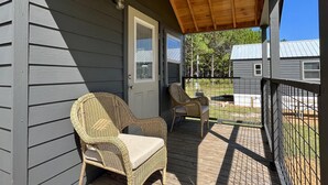 A covered porch with two wicker chairs and a wooden deck.