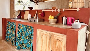 A kitchen with a wooden counter, a hanging basket, a bottle, and a fruit basket.