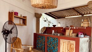 A kitchen with a wooden chair, a fan, and a hanging basket.