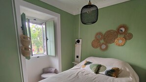 Ein Schlafzimmer mit Bett, Fenster, einer Pendelleuchte und Wanddekorationen.