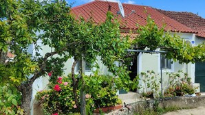 Ein Haus mit rotem Ziegeldach, umgeben von üppigem Grün und blühenden Pflanzen.