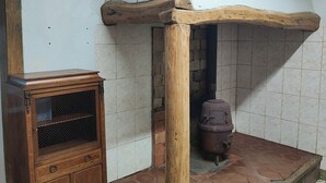 Ein Zimmer mit einem Holzkasten, einer Fliesenwand und einem Backsteinofen.