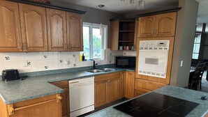 A modern kitchen with wooden cabinets, a built-in microwave, a dishwasher, and a black induction cooktop. - Large newly renovated house.  Cozy and convenient.  (Valemount)