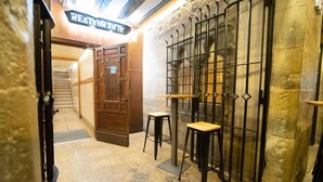 A narrow hallway with a wooden door labeled "RESTAURANTE" leading to a dining area. There are two stools and a small table in the hallway. - Casa Otano (Pamplona)