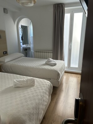 A hotel room with two beds, a bathroom, and a view of the outside. - Casa Otano (Pamplona)
