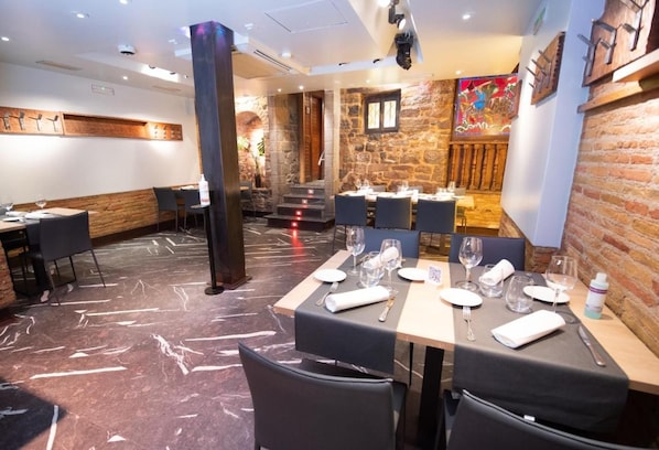 A restaurant with marble flooring, stone walls, and modern furniture. - Casa Otano (Pamplona)