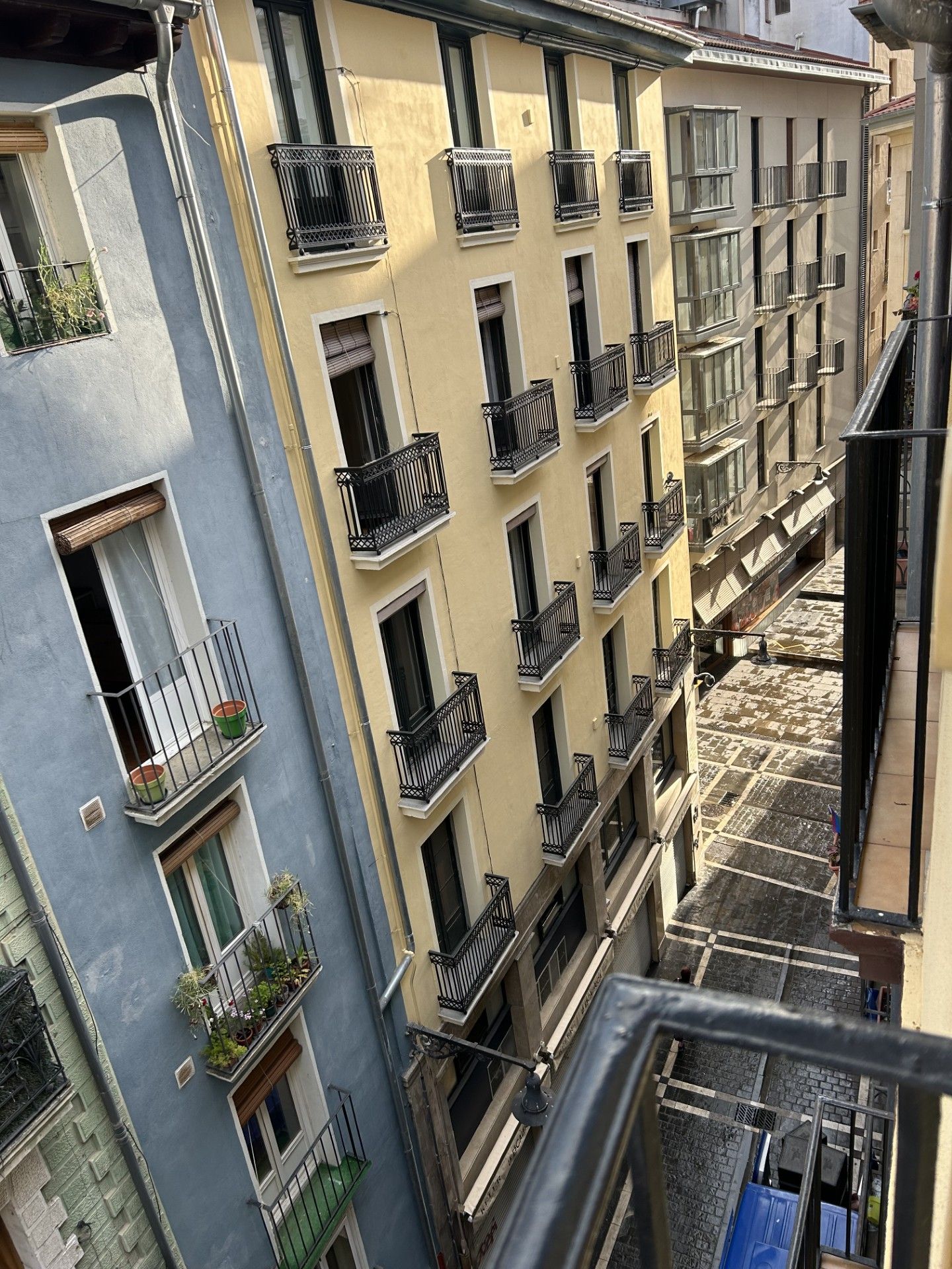 Un edificio de varios pisos con balcones, una escalera y una calle estrecha.