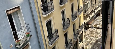 Un immeuble à plusieurs étages, doté de balcons, d’un escalier et bordé d’une rue étroite.