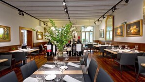 A restaurant with multiple tables set for dining, featuring a central floral arrangement and wine bottles on the tables. - Casa Otano (Pamplona)