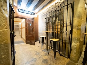 A narrow hallway with a wooden door labeled "RESTAURANTE" leading to a dining area. There are two stools and a small table in the hallway. - Casa Otano (Pamplona)