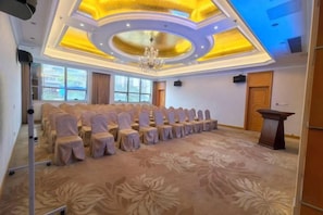 Una sala conferenze con file di sedie, un podio e un lampadario.