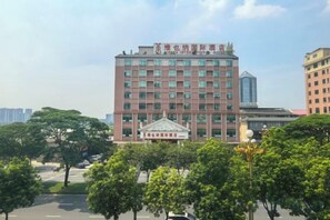 A multi-story building with a central entrance and a surrounding landscaped area with trees. - Vienna International Hotel (Dongguan Mayong Central Avenue) (Dongguan)