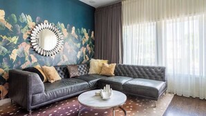 A modern living room with a dark leather sectional sofa, a round coffee table, and a large mirror on the wall. - Duplex 3 Bed 2 Bath Apt Steps from Lincoln Square (Chicago)