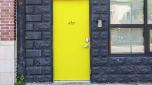 A building with a bright yellow door, numbered 4327, and a stone facade. - Duplex 3 Bed 2 Bath Apt Steps from Lincoln Square (Chicago)