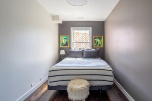 A bedroom with a bed, a window, and two framed pictures on the wall.