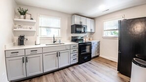 Una cocina moderna con armarios blancos, un refrigerador negro y un microondas.