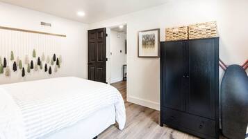 Een slaapkamer met een bed, een kledingkast, een deur en een wandplant.