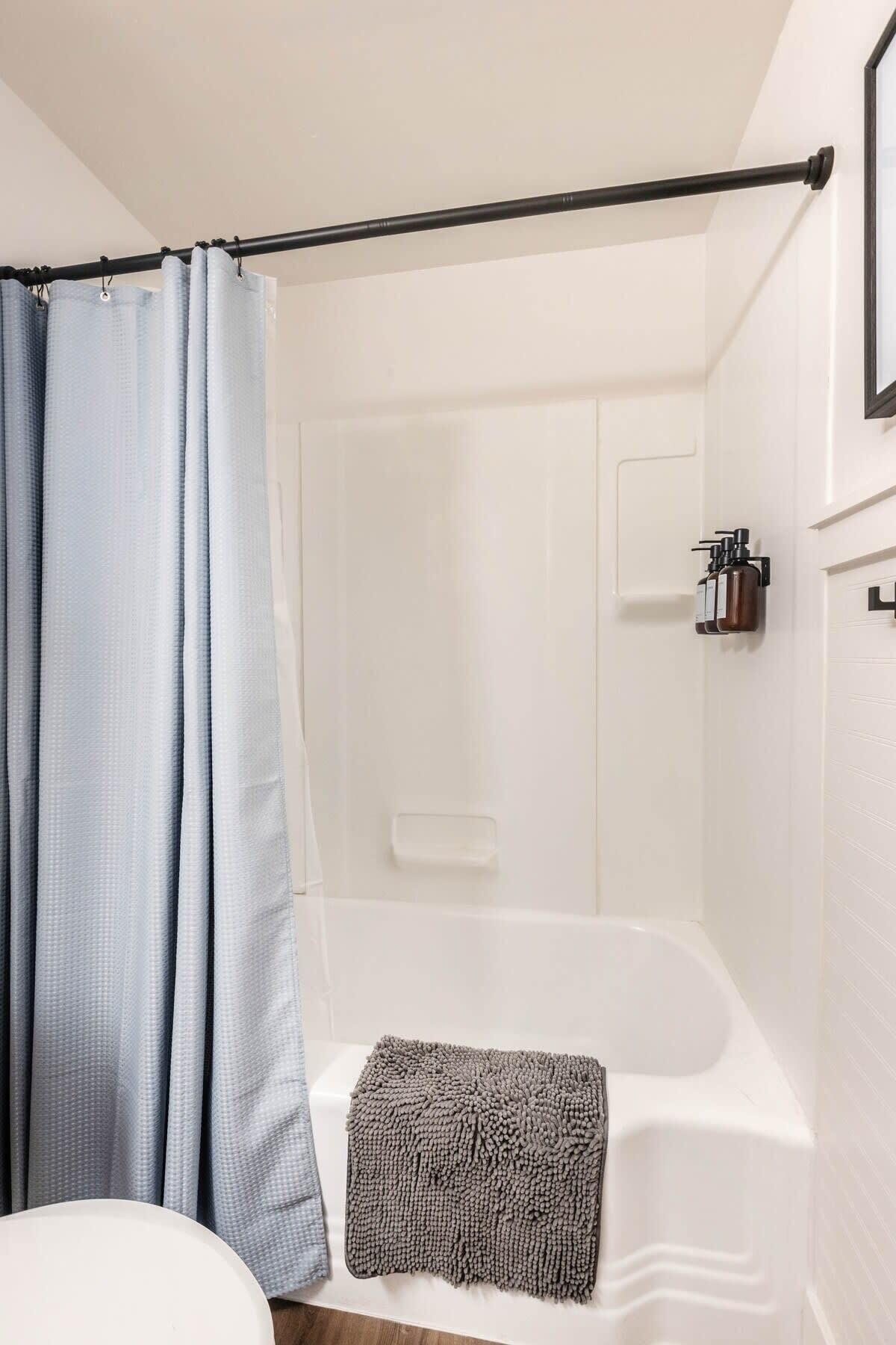 Une salle de bain avec une baignoire, un rideau de douche, une serviette et un distributeur de savon.
