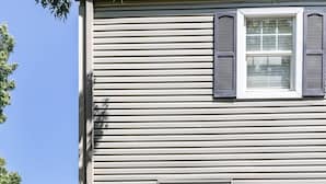 Una casa de dos pisos con una puerta principal negra, un buzón y el número 240 en la pared.