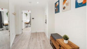 Ein zeitgemäßer Flur mit einer Holzbank, einem Blumentopf und Kunstwerken an den Wänden.