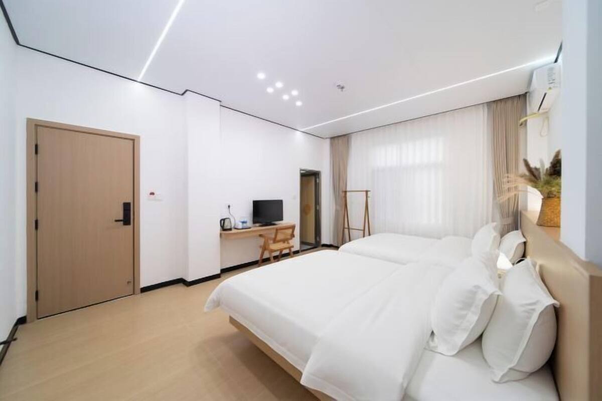 Een hotelkamer met een groot bed, een bureau met een computer, een televisie en een raam met gordijnen.