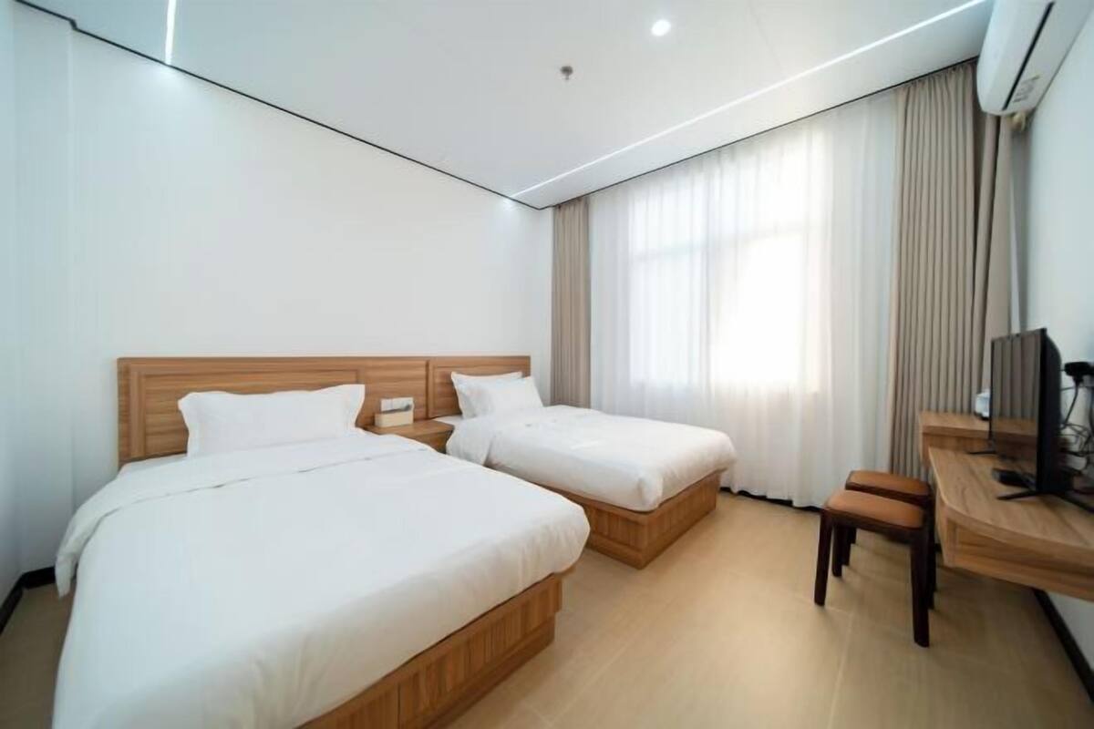 Een hotelkamer met twee bedden, een bureau en een stoel.