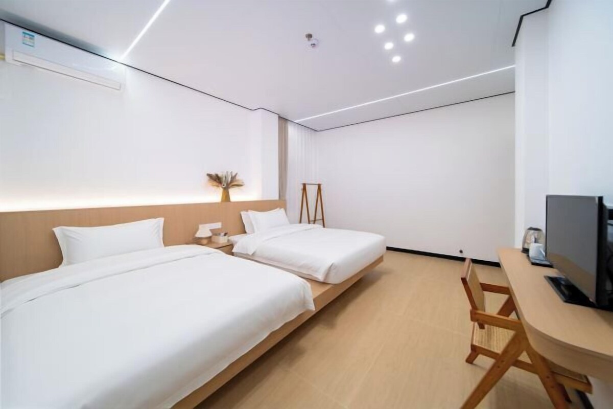 A modern hotel room with two beds, a desk, and a television.
