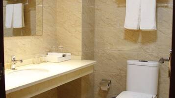 A bathroom with a marble sink, a toilet, and a mirror.
